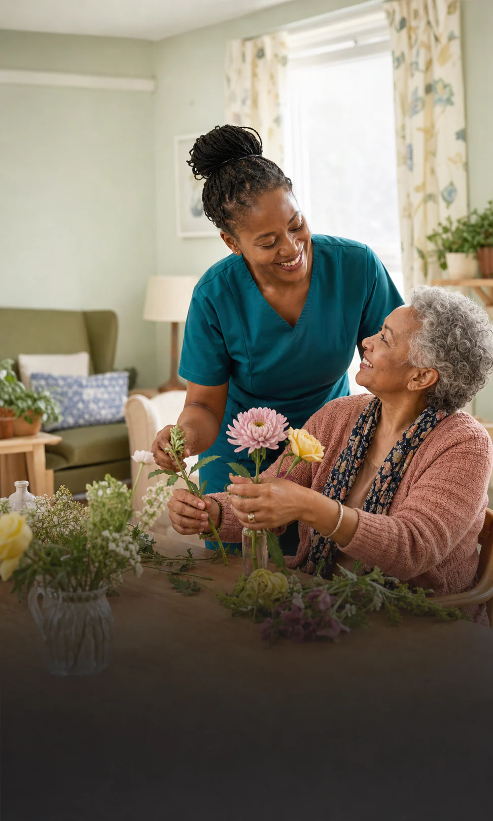 Black care professional arranging flowers with an older mixed-race woman